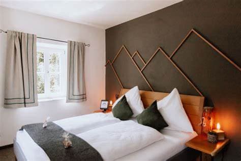 Modernes Schlafzimmer mit hölzerner Bergsilhouette an einer dunklen Wand und weißer Bettwäsche.